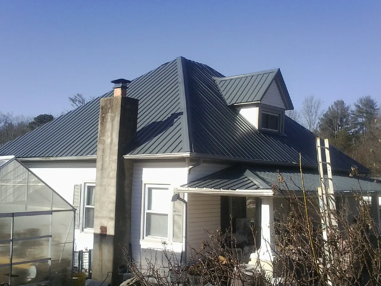 Dark blue standing seam metal roof on a white farmhouse with dormer — Slate & Tile Roof Repair by Roofing Brothers in McCammon