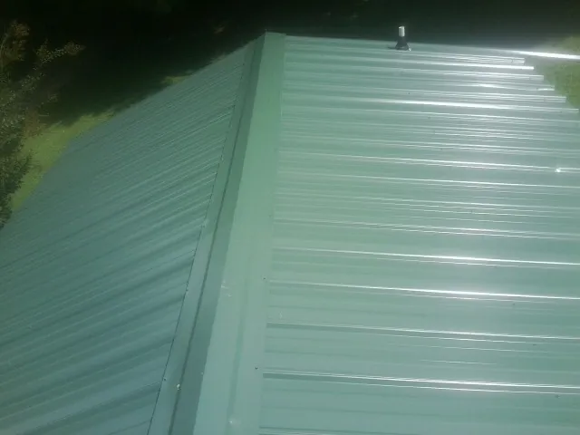 New green metal panels meeting at the ridge of a roof — Flat Roof Repair work by our crew in McCammon