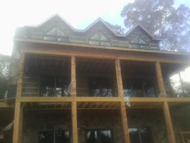Dormers and porch framing on a large log home under construction — Roof Coating work by our crew in McCammon