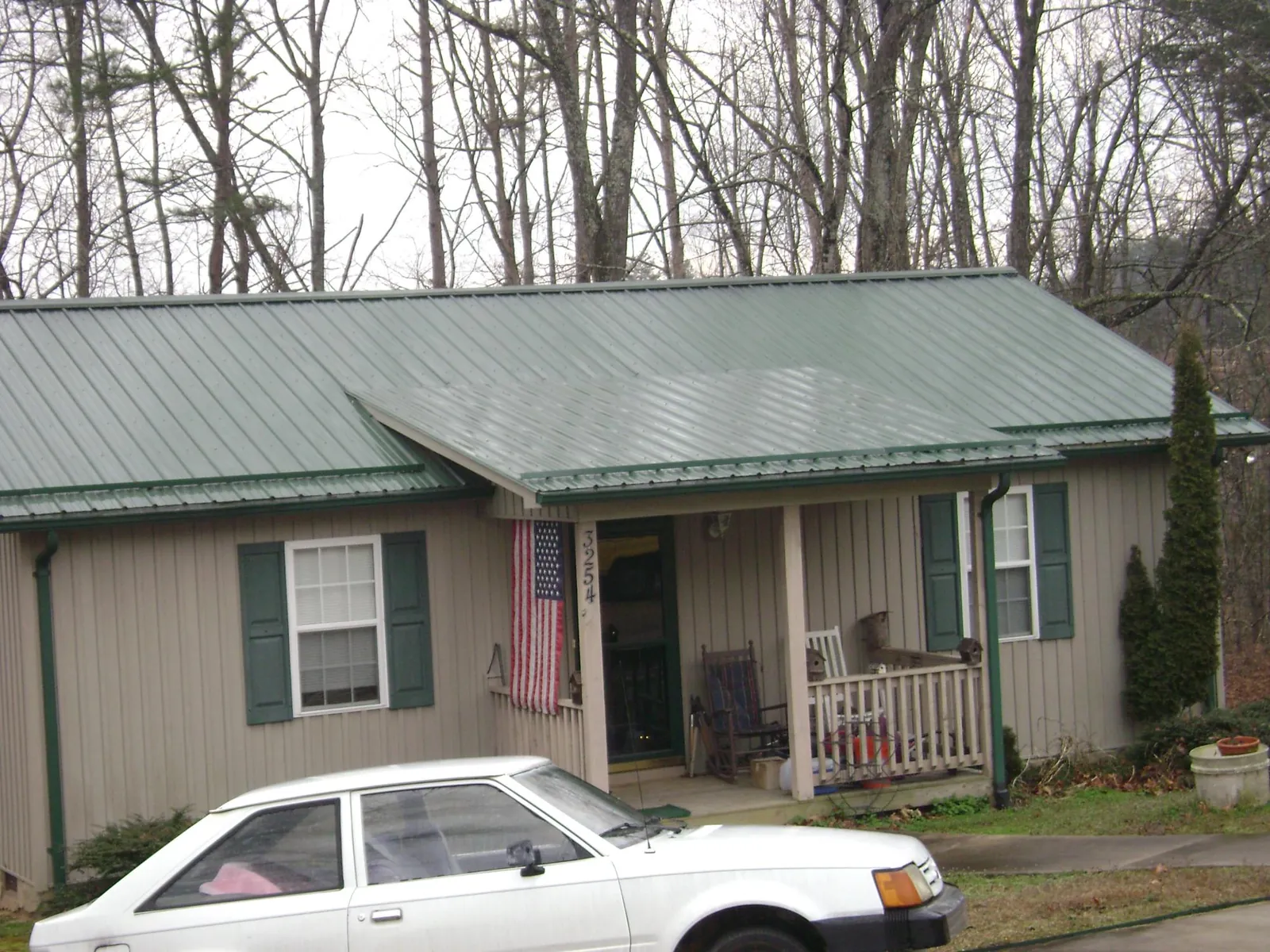 Green metal roof and front porch on a tan sided cottage in McCammon