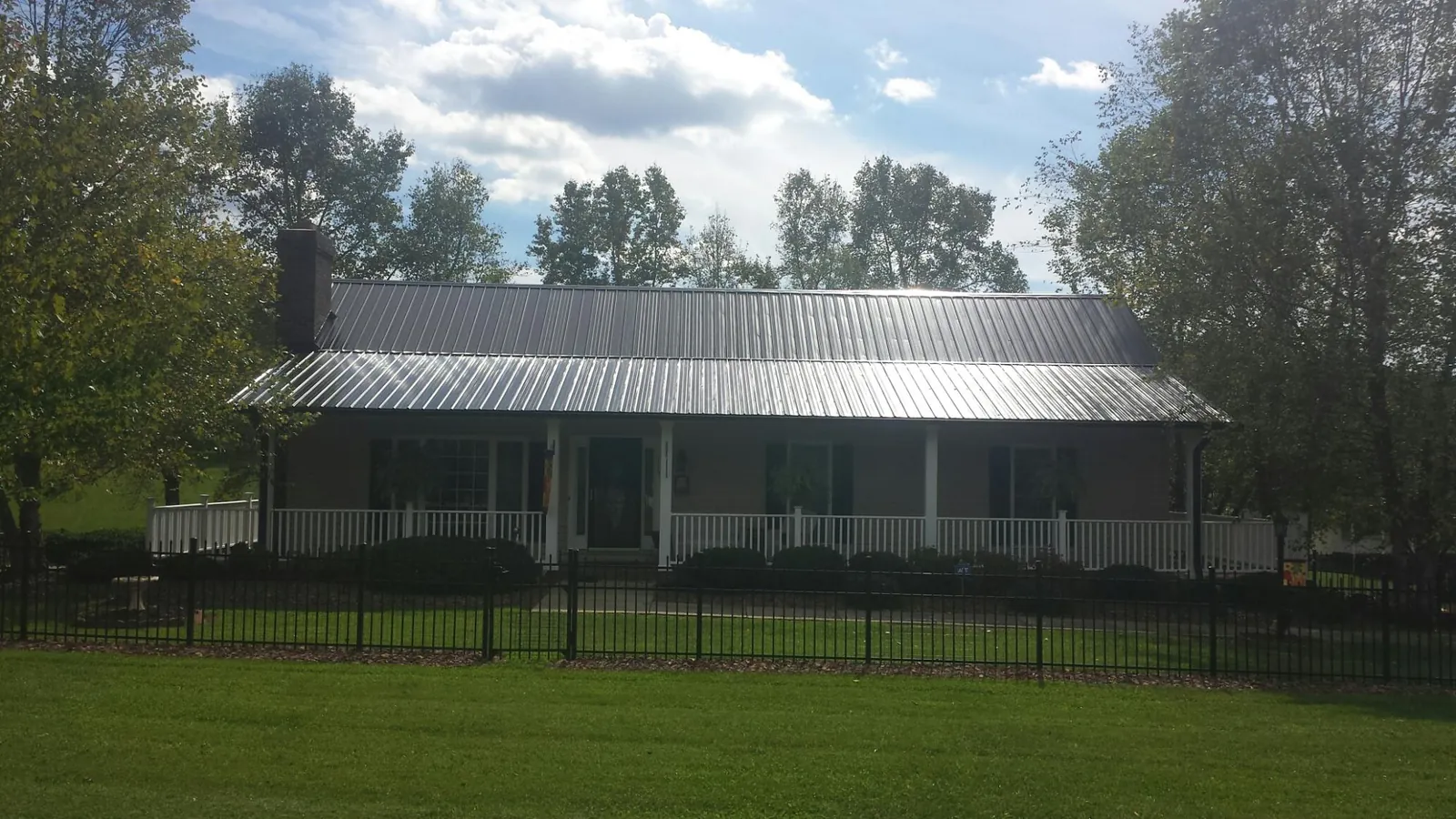 Gray metal roof on a brick ranch with a full width front porch — Gutter Guard Installation work by our crew in McCammon